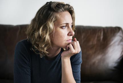 Woman sitting on her couch, struggling with mental health.