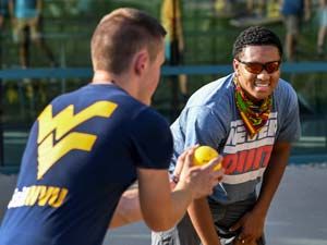 Two male Summer students playing a game with a yellow ball.